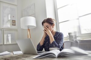 tired stressed businesswoman at laptop with head in hands 742168607 464da453fe9742ed9c4354004df56a56