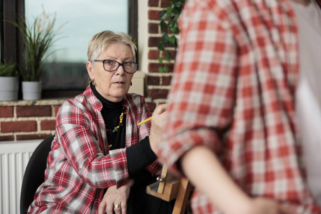 senior woman student involved art activity creating artwork creative workshop retired lady visiting drawing class learning draw classroom social hobbies older meet people